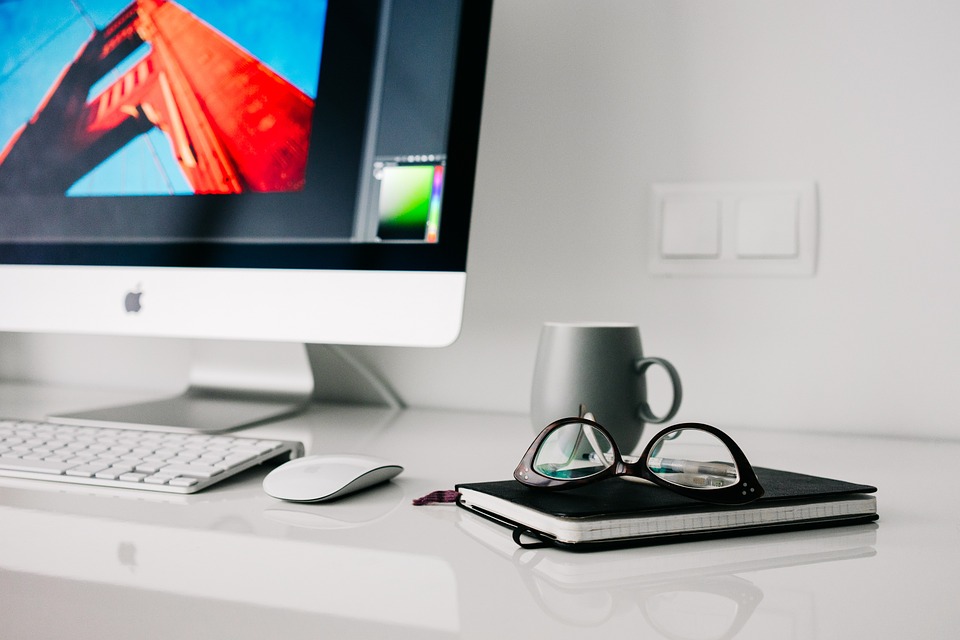 White Desktop With Display, Keyboard, Coffee Cup, Glasses